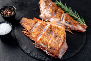 grilled red sea bass with rosemary and spices on a stone background 