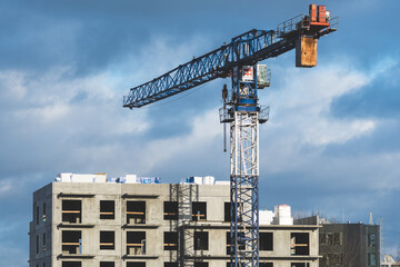 Worksite with cranes, new buildings or houses under construction with cloudy sky in the background