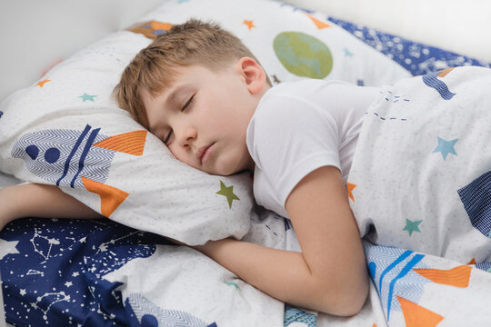 Little boy preteen sleeping in his bed in sunny bedroom in the morning.