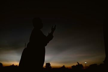 Silhouette Young asian muslim man praying on sunset,Ramadan festival concept