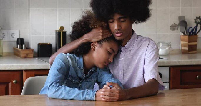 African teenagers 18s couple sit indoors, older brother calming his younger sister, hugs, express sympathy, speaks words of encouragement, provide help. Best friends, support, empathy, bond concept
