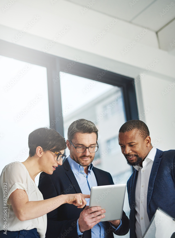 Poster Teamwork and technology - invaluable business assets. Shot of a team of colleagues using a digital tablet together at work.