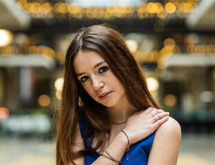 Fashion portrait of an 18 year old red haired pretty girl sitting legs crossed in a short blue dress