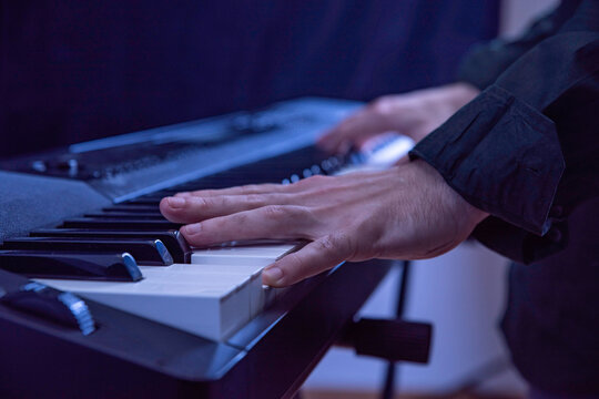 Male hands playing electric Digital Piano. Musician man with black guitar at a rock concert