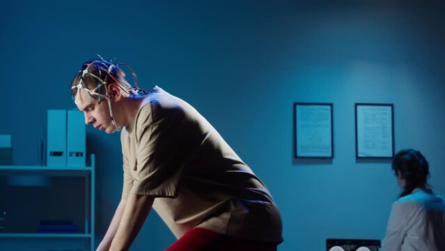 EEG topographer for examining brain, doctor making electrogram of scalp activity. Researching of brain work, man riding bicycle in electroencephalography headset. Rehabilitation after damage in sport.