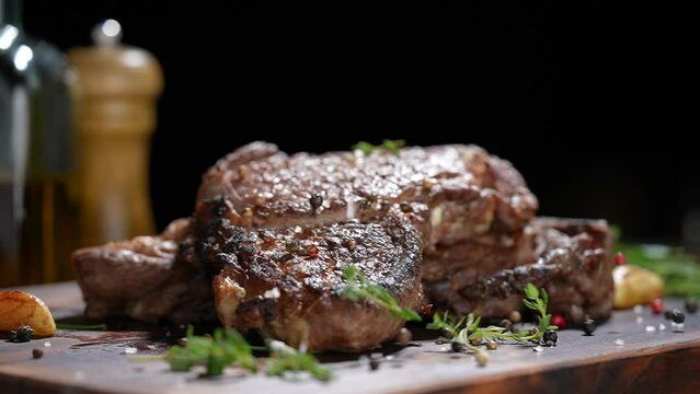 Cooked juicy steak meat beef with seasoning dropped on wooden chopping board. slow motion