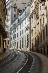 Naklejka premium Lisbon, Portugal - 12 28 2018: Empty bending streets and railway tracks with typical old houses