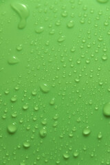 Fototapeta na wymiar Green pastel water drops on light shiny surface