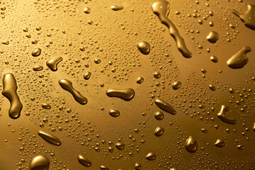 Fototapeta na wymiar Golden metal water drops on shiny metallic surface 