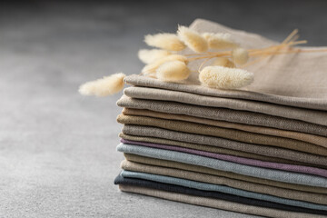 A pile of four folded dull-colored natural linen fabric