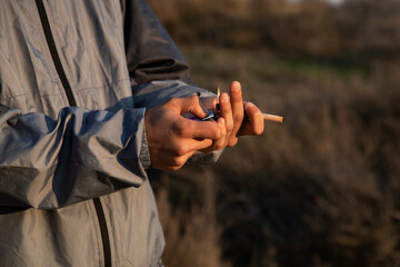 Close-up of a boy's hands lighting a marijuana joint with a lighter