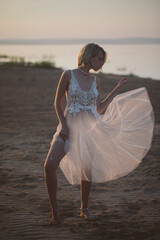 Fototapeta na wymiar Happy blond Woman in white dress Enjoying Beautiful Sunset on th