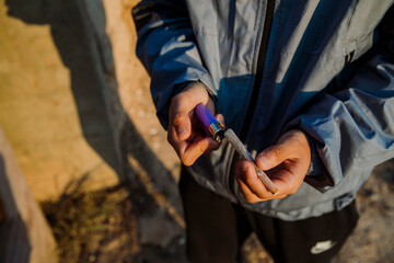 Close-up of the hands of a young boy holding a marijuana cigarette