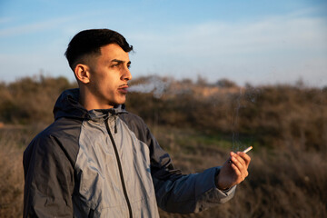 Close-up of young man smoking a marijuana joint outdoors