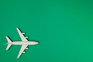 Airplane model. White plane on green background. Travel vacation concept. Summer background. Flat lay.