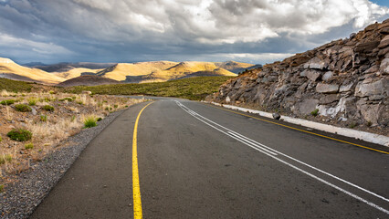 Travel to Lesotho. Well maintained road and threatening storm over the mountains