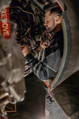 Fototapeta na wymiar Bearded man aviation maintenance technician checking airplane components while working at repair station