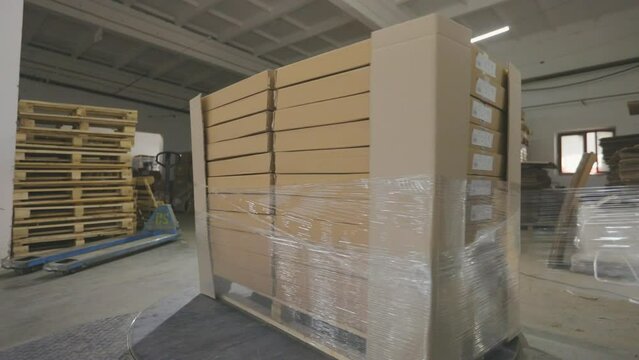 A special machine wraps boxes in polyethylene film. Packaging boxes with products in plastic film at the factory.