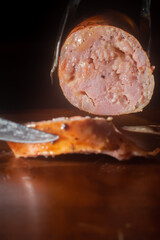 Sausage sliced into a wooden table, made with cheese and pieces of Italian pepperoni, copy space and selective focus, barbecue concept
