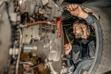 Fototapeta na wymiar Male worker aviation maintenance technician using wrench while repairing airplane at repair station