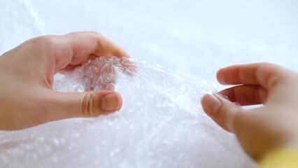 ASMR, woman presses plastic bubble wrap as a stress relief. Popping bubble wrap