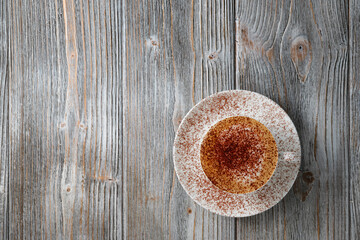 Cappuccino on wooden background flat lay. Coffee with milk sprinkled with coffee powder, copy space. Fragrant cappuccino in white cup flat lay gray wood background.