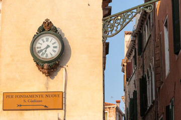 Fototapeta na wymiar An antique clock on building's wall, Venice, Italy