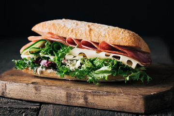 homemade sandwich with ham, cheese and lettuce on a rustic wooden board, selective focus