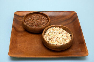 Flax seeds and oatmeal in a wooden bowl on a wooden tray