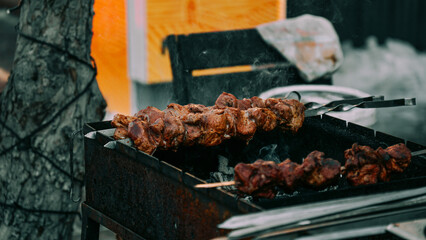 Closeup of some meat skewers being grilled in a barbecue outside on street food market