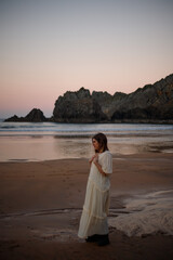 young girl enjoying the sunset on the beach in a long dress