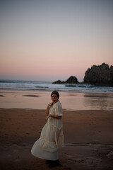 Fototapeta na wymiar young girl enjoying the sunset on the beach in a long dress