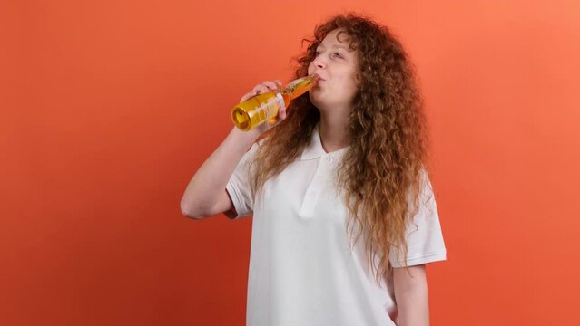Close up video of a fan football woman with cutly red hair holding a bottle of beer and drinking being on the favourite team match.