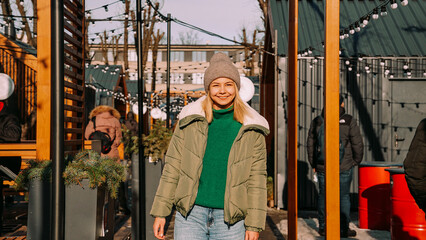 Beautiful blonde woman looks up with a smile while standing outdoors. Perfect weather for hanging out with friends. Urban art space with street food