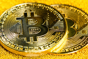 Two golden bitcoins on yellow gold placer surface. Crypto currency. Bitcoin mining concept