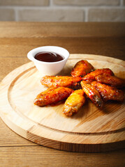 Hot Bbq. Grilled chicken wings with tomato sauce on wood board. Barbecue food. Baked chicken wings in the Asian style on plate. Roasted hot and spice food. Restaurant serving. Copy space. Close up