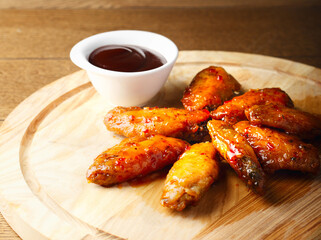 Hot Bbq. Grilled chicken wings with tomato sauce on wood board. Barbecue food. Baked chicken wings in the Asian style on plate. Roasted hot and spice food. Restaurant serving. Copy space. Close up
