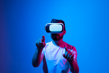 Excited bearded man experiencing virtual reality via VR headset and touching something, stretching and zooming with his hands.