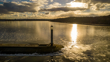 Aerial view of a pier with a lighthouse on a frozen lake