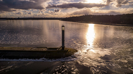 Aerial view of a pier with a lighthouse on a frozen lake