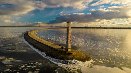 Aerial view of a pier with a lighthouse on a frozen lake