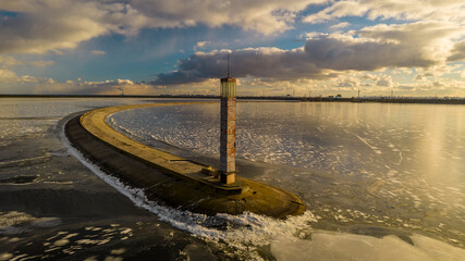 Aerial view of a pier with a lighthouse on a frozen lake