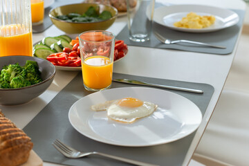 Breakfast closeup with eggs, wholegrain bread, fresh broccoli, and orange juice