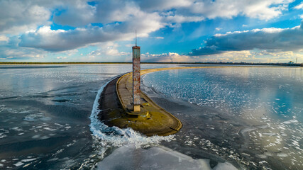 Aerial view of a pier with a lighthouse on a frozen lake