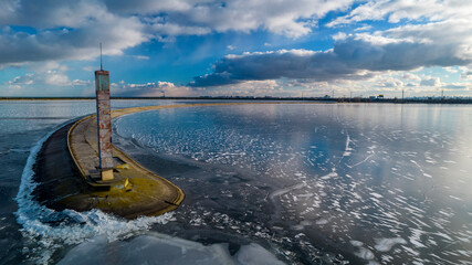 Aerial view of a pier with a lighthouse on a frozen lake