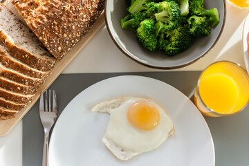 Breakfast closeup with eggs, wholegrain bread, fresh broccoli, and orange juice