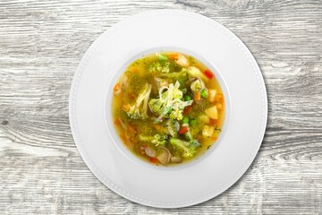 Tasty noodle soup with vegetables in bowl on the desk