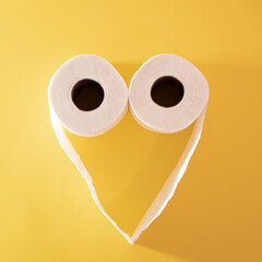 Toilet paper in the shape of a heart on a yellow background. Love concept