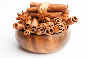 Obraz na płótnie Canvas Anise stars and cinnamon sticks in a wooden bowl isolated on white background. Aromatic spices