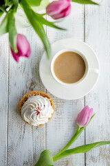 Tulips and a sweet dessert with a cup of coffee on grey wooden table,flat lay. Morning romantic breakfast.